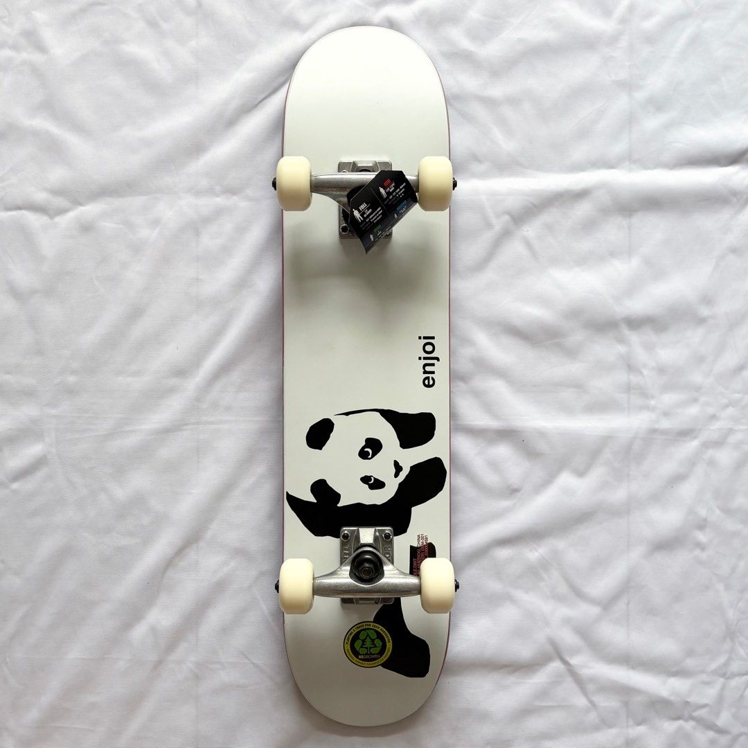 Compact skateboard with a panda graphic, silver trucks, and cream wheels viewed from above on white fabric.