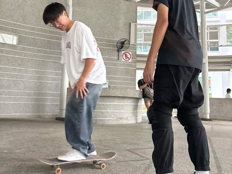 A coach closely observing a rider practising on a skateboard